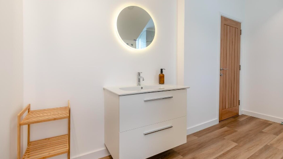 Bathroom basin and illuminated mirror — Apartment 9